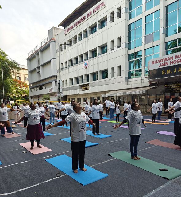 Group performing yoga stretches outside Bhagwan Mahaveer Jain Hospital