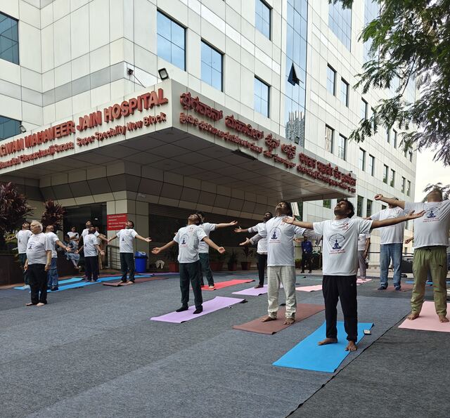 Group stretching with arms raised outside the hospital